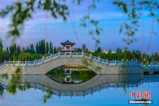 资料图：甘肃敦煌飞天公园水清草绿，迷人的大漠水景引游人游园散步。 王斌银 摄