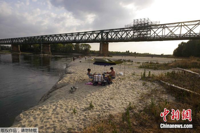 2022年6月27日，在意大利帕维亚附近的利纳罗洛，人们在贝卡桥(Becca Bridge)旁的波河河床上放松。由于缺少雨水，该流域变成了一大片沙滩。